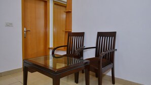 A dining area with a glass-top table and two wooden chairs. - Hotel White Pearl (New Delhi)