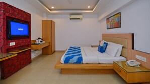 A hotel room with a bed, a TV, a desk, a wardrobe, and an air conditioning unit. - Hotel White Pearl (New Delhi)