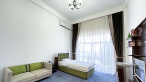 Hotellihuone, jossa on sänky, sohva, televisio ja ilmastointilaite.