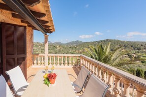 Ein Balkon mit Tisch für zwei Personen, mit Blick auf eine gebirgige Landschaft.