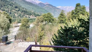 A mountain view with a stone wall and a metal railing in the foreground. - Private Room in Manali, Mountain and River view Near Manali-4 (Bashisht)