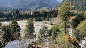 A mountainous landscape with a river, dense forests, and a village in the valley. - Private Room in Manali, Mountain and River view Near Manali-4 (Bashisht)