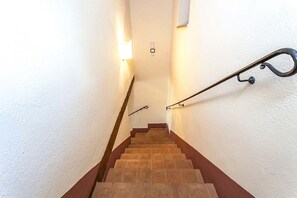 A staircase with a handrail, a light switch, and a wall-mounted light fixture. - Fratta Apartments (Cortona)
