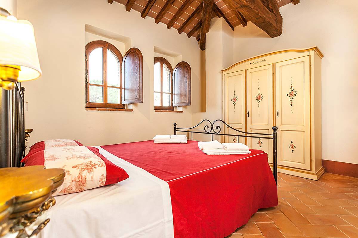 A bedroom with a bed, a wardrobe, and two windows.