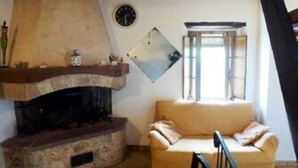 Un salon chaleureux avec une cheminée en pierre, un canapé et une horloge murale.