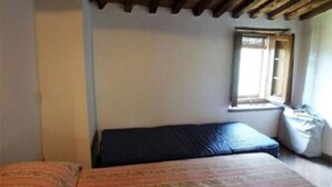 Une petite pièce simple, avec un lit, une fenêtre et un plafond en bois.