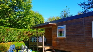 A wooden cabin with a covered outdoor seating area and a small table. - Cottage Family (Crêches-sur-Saône)