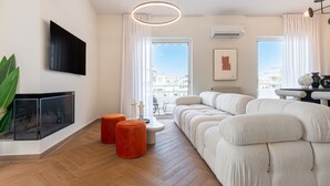 Ein modernes Wohnzimmer mit einer großen Couch, einem Flachbildfernseher und einem Essbereich mit Tisch und Stühlen.