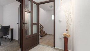 A room with a wooden door, a chair, a vase with branches, and a staircase in the background. - Apartment with pool in Medulin A6 (Medulin)