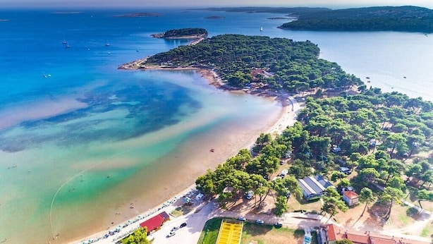 An aerial view of a coastal area with a beach, boats, and a forested island. - Apartment with pool in Medulin A6 (Medulin)