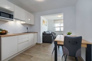 A modern kitchen with white cabinets, a wooden countertop, and a dining area with a table and chairs.