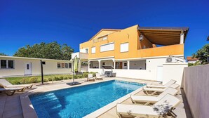 A modern house with a swimming pool, lounge chairs, and a covered patio. - Apartment with pool in Medulin A6 (Medulin)