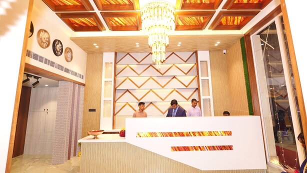 A reception area with a modern design, featuring a central desk, a chandelier, and a patterned wall.