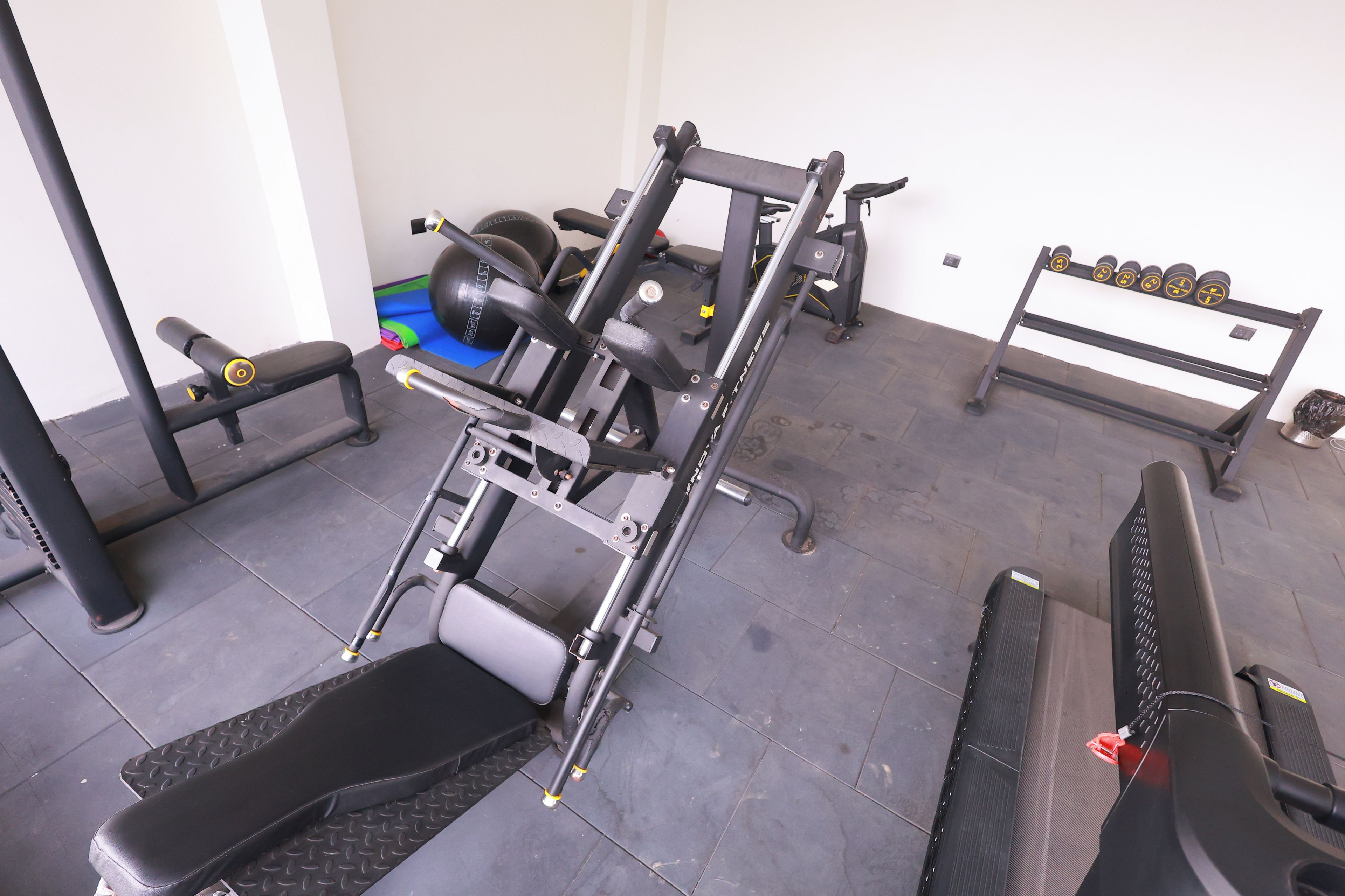 Un gimnasio con equipo de ejercicio, una banca y accesorios para levantamiento de pesas.