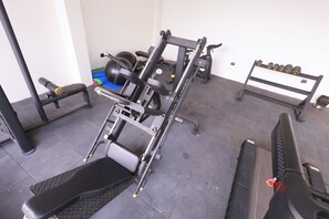 Un gimnasio con equipo de ejercicio, una banca y accesorios para levantamiento de pesas.