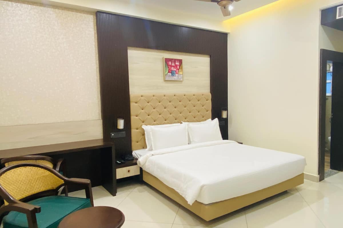 Una habitación de hotel con cama, escritorio, silla y una mesita.