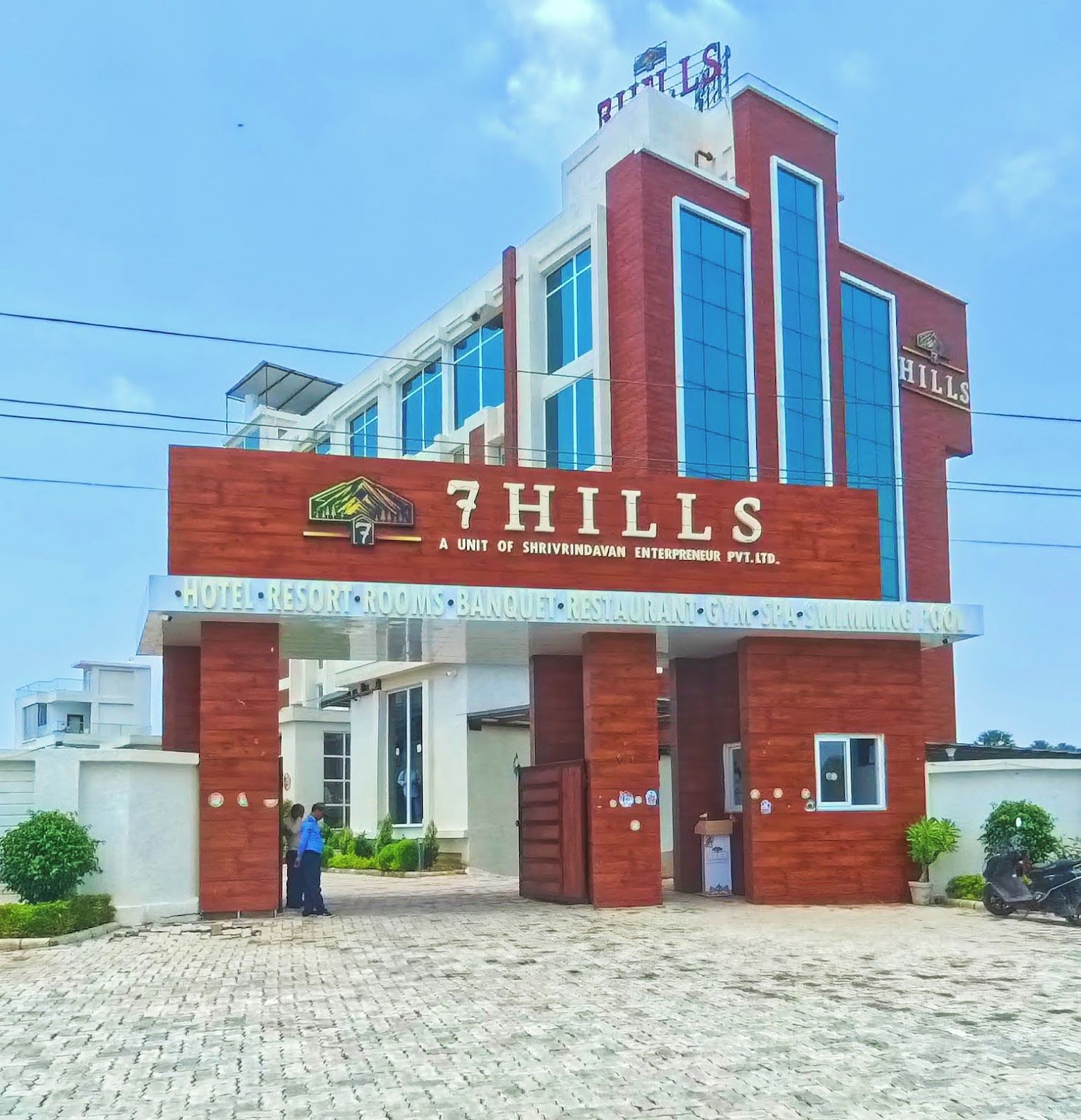 A hotel named '7HILLS' with a sign indicating it is a unit of Shrivindavan Entrepreneur Pvt. Ltd.