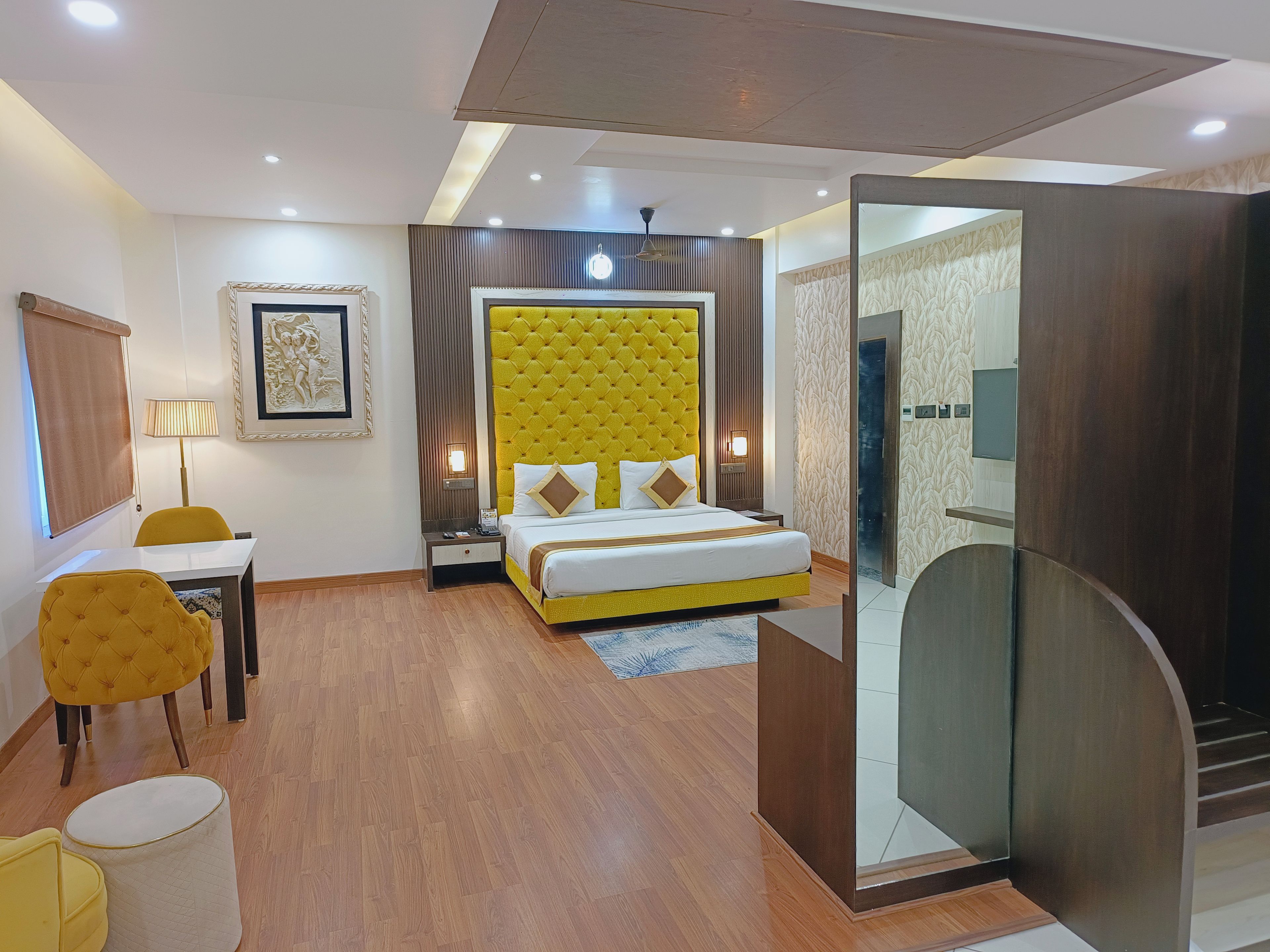 Une chambre d’hôtel avec un lit, un bureau, une chaise, une lampe et un miroir.
