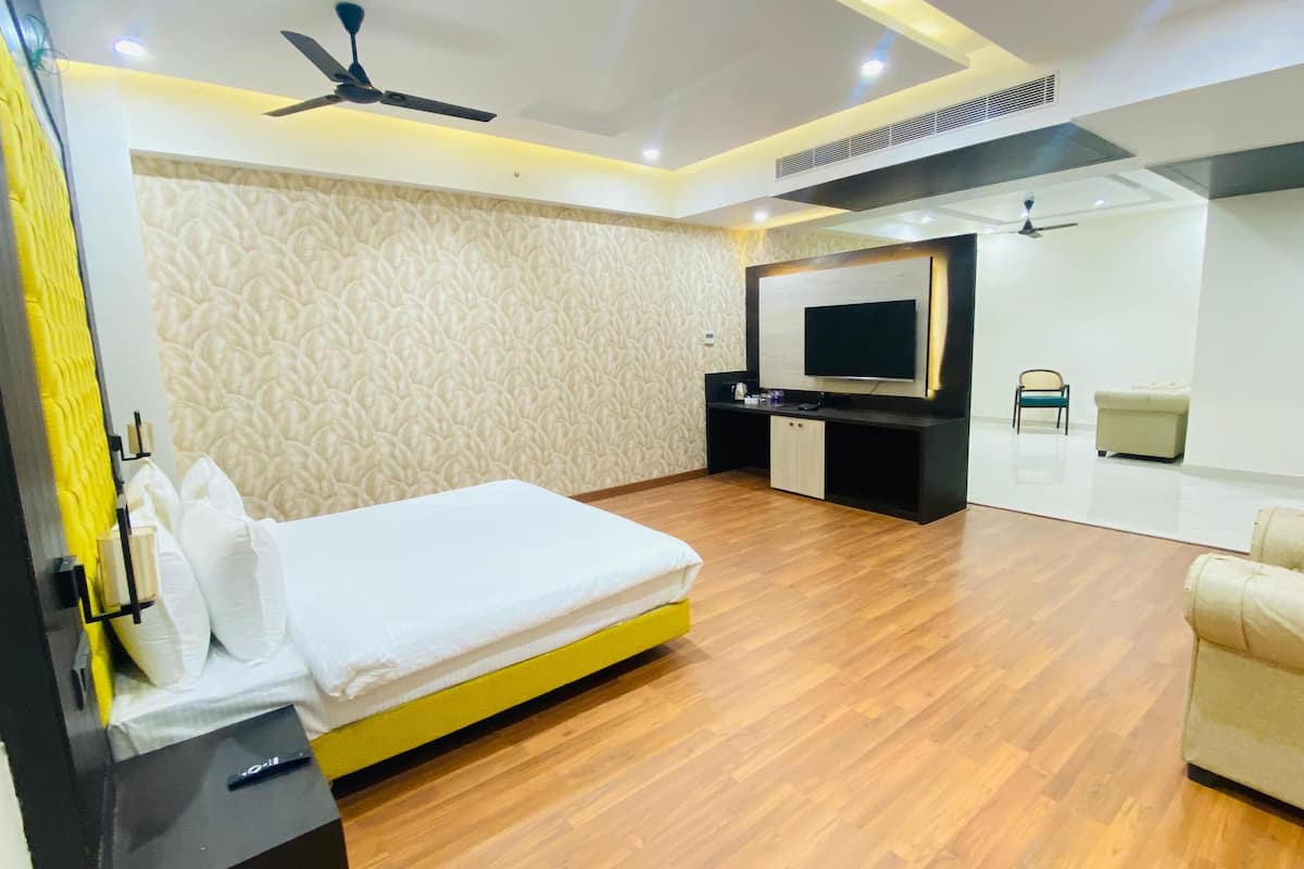 Una habitación de hotel moderna con cama, televisor, sofá y espejo.