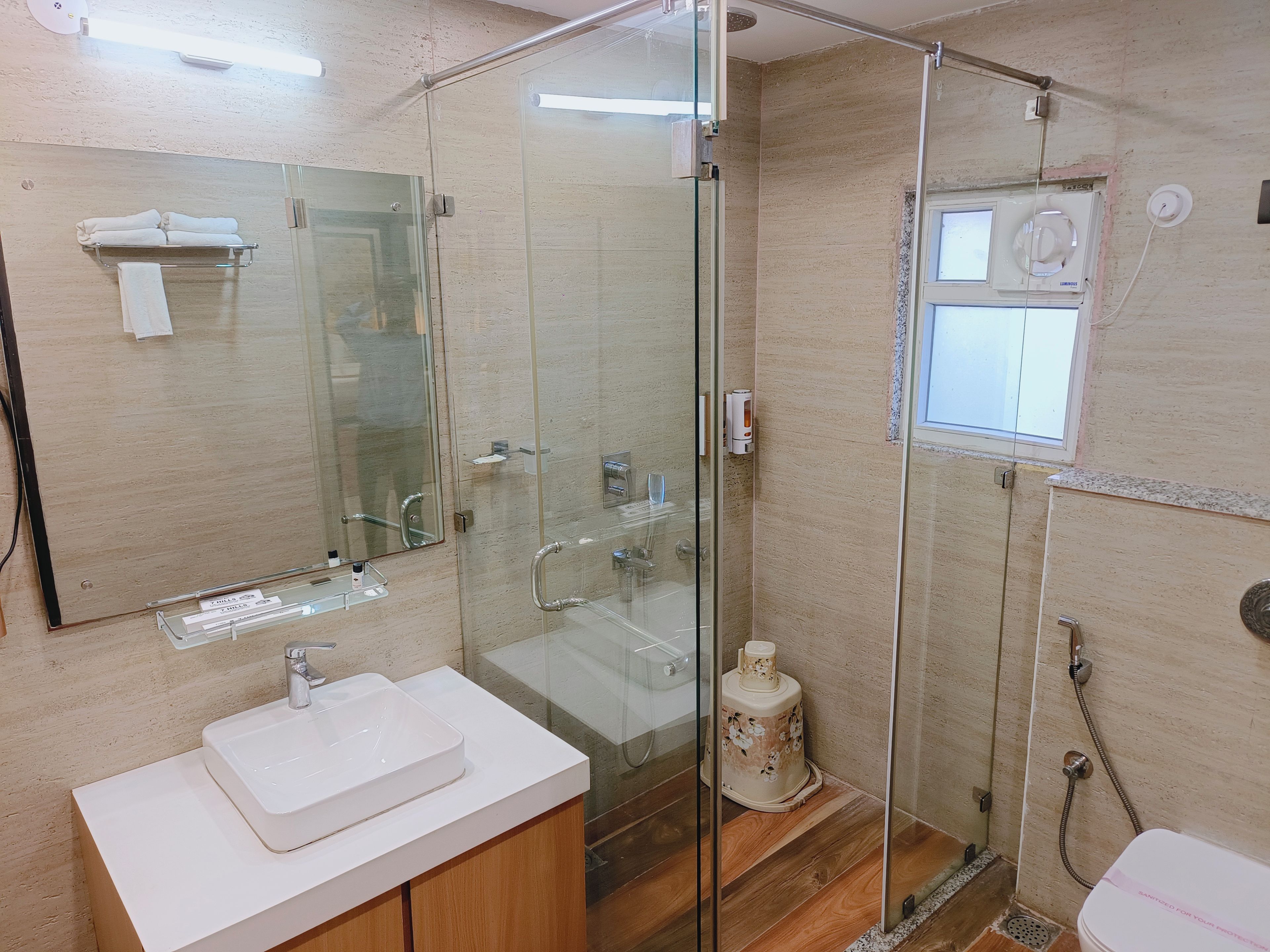 Un baño moderno con ducha acristalada, lavamanos blanco y espejo.
