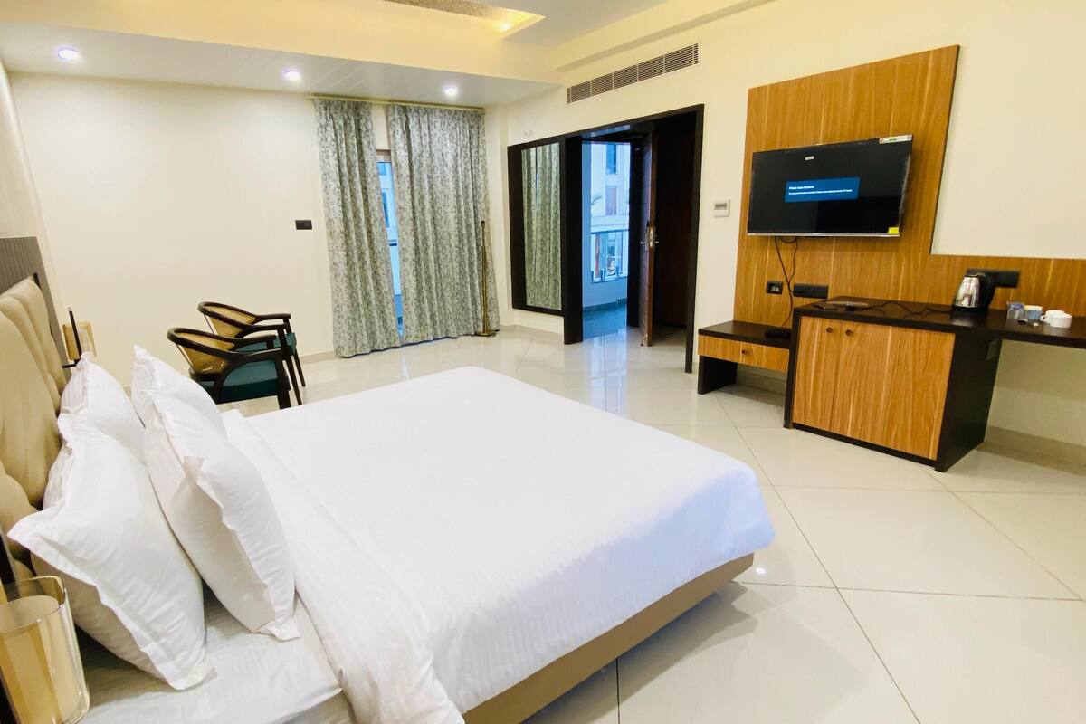 Habitación de hotel con una cama grande, un escritorio, un televisor y vistas al exterior.