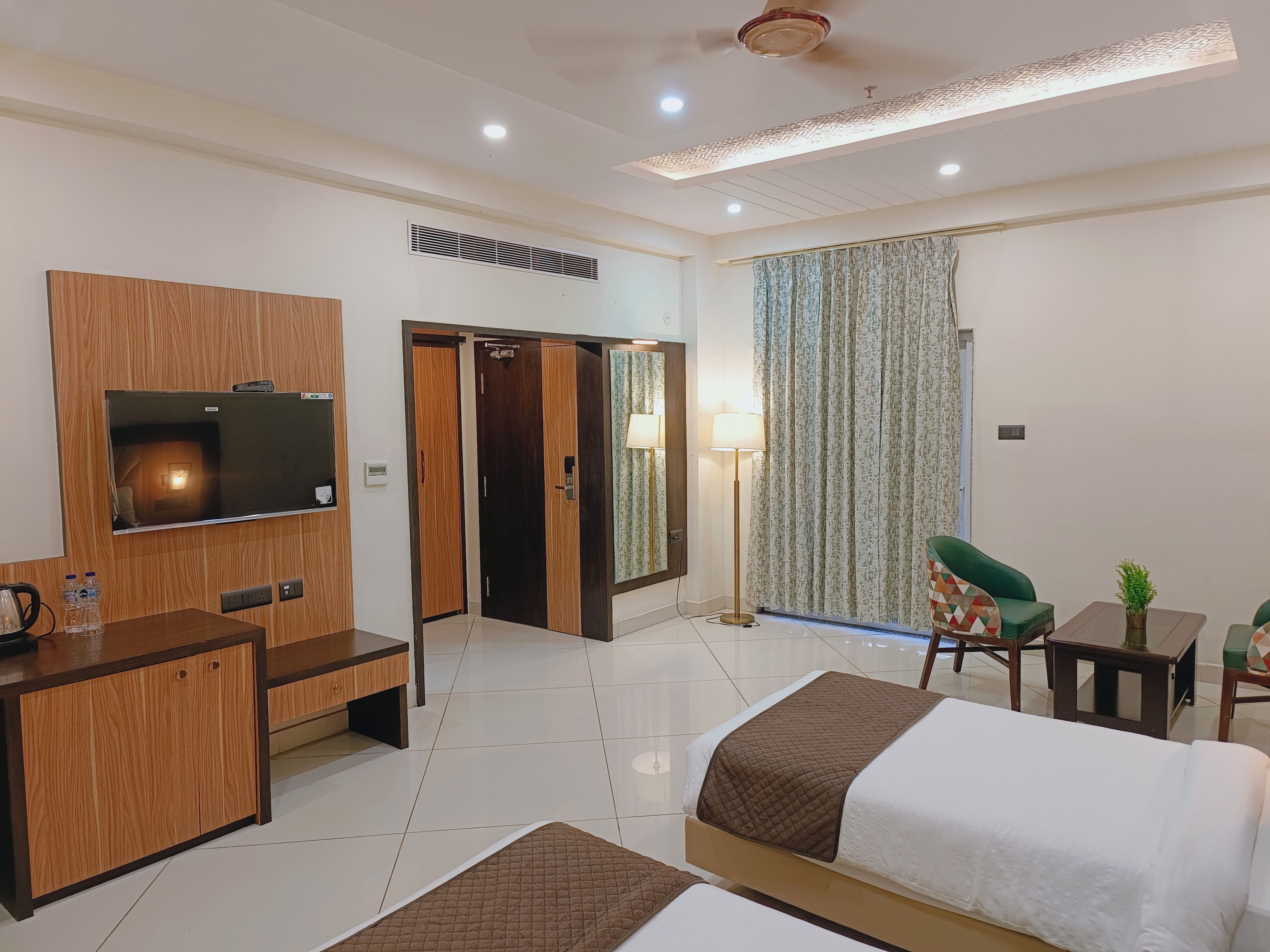 Quarto de hotel com cama, escrivaninha, televisão, espelho e porta que dá para outro cômodo.