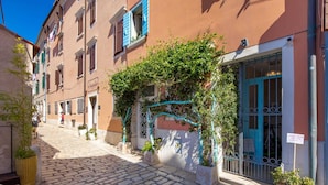 A cobblestone street with buildings, a blue gate, and potted plants. - Natascha ’s Beachfront/Stylish Two-Story Apartment A2 (Rovinj)