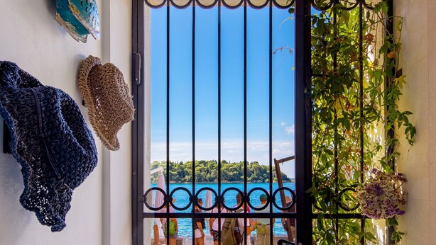 A gate with a view of a body of water and people in the distance. - Natascha’s Beachfront/Stylish Two-Story Apartment A2 (Rovinj)