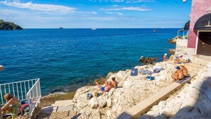 A coastal scene with rocky terrain, a clear blue sky, and a calm sea. - Natascha’s Beachfront/Stylish Two-Story Apartment A2 (Rovinj)