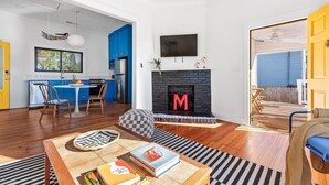 A modern living room with a fireplace, a dining area, and a kitchen. - Suite Tea (Atlanta)