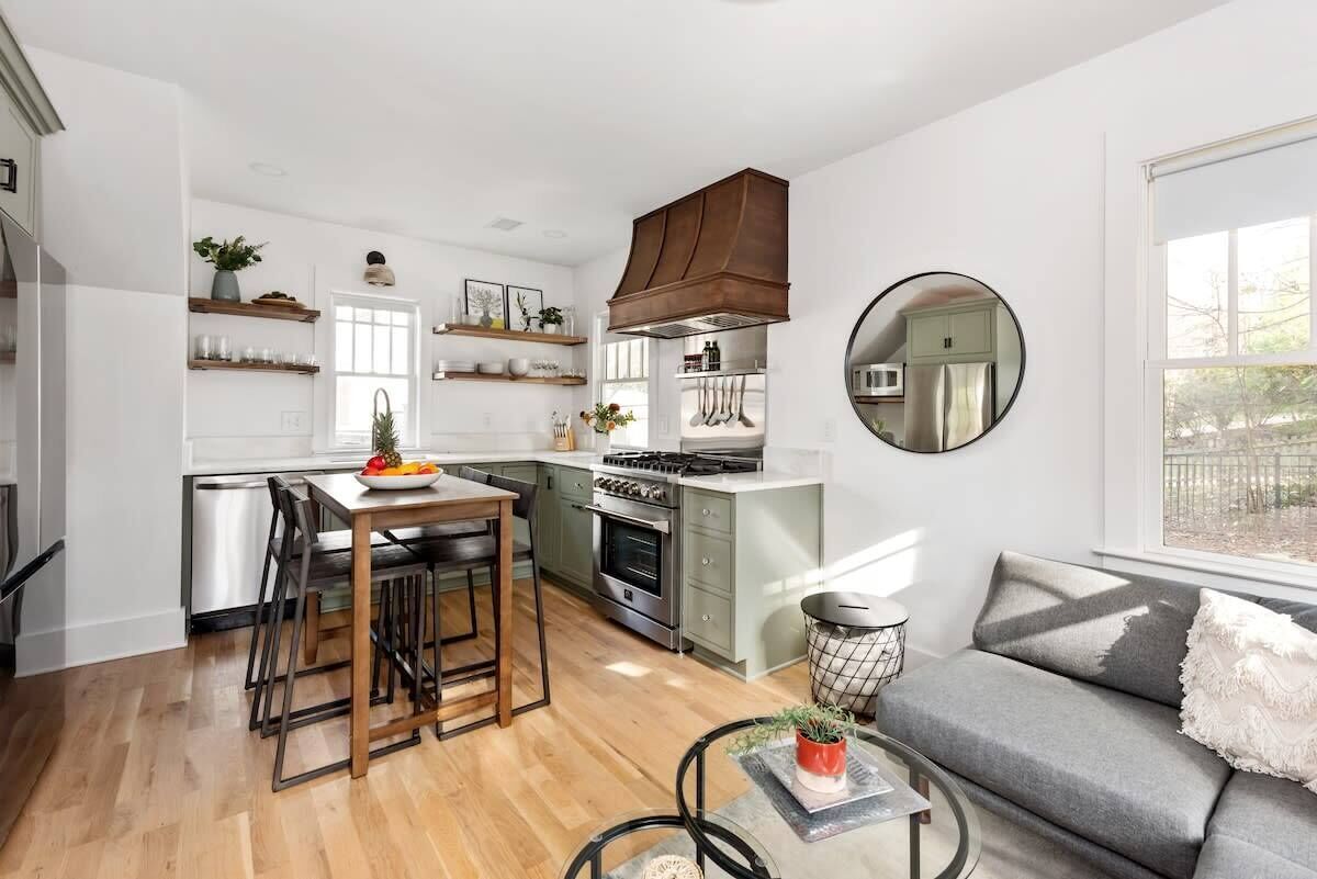 A compact kitchen with a dining area, a built-in oven, and a large window providing natural light.