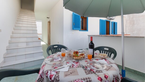 A dining area with a table set for two, a bottle of wine, and a plate of food. - 3678 A Casa di Vito by Barbarhouse (Salve)