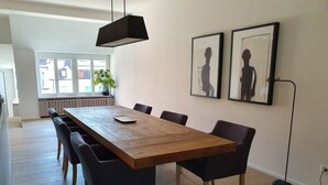 Un comedor con una mesa de madera, seis sillas y dos cuadros en la pared.