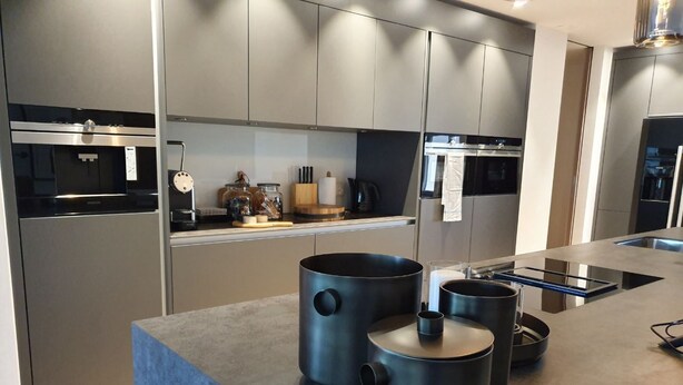 Una cocina moderna con electrodomésticos integrados, una isla grande con ollas negras y un diseño elegante.