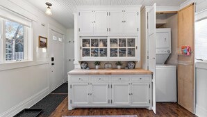 Una cocina con muebles blancos, encimera de madera y ventana con vistas.