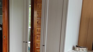 Een kamer met een grote witte inbouwkast, een houten deur en een kamerbreed tapijt met dessin.