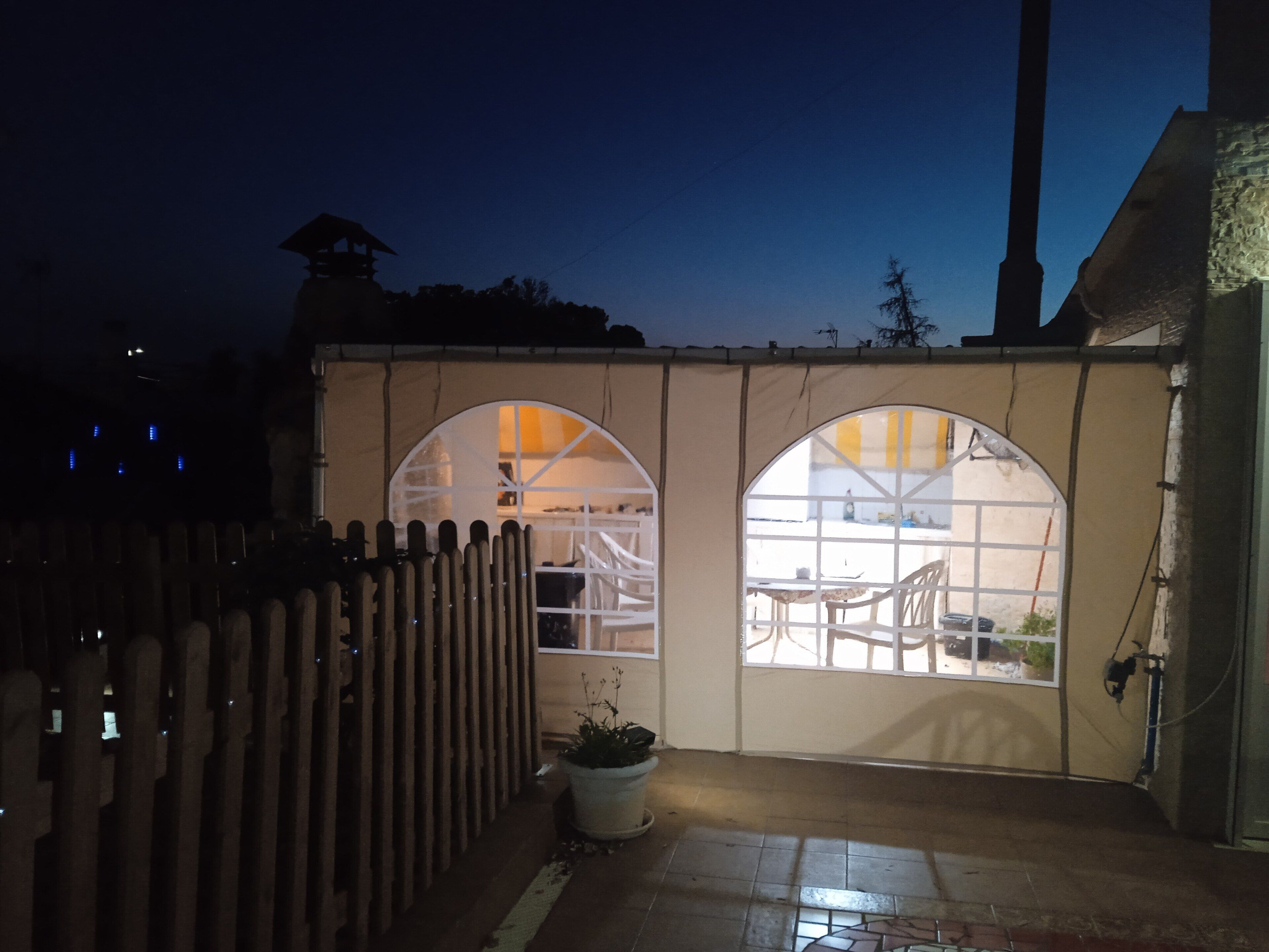 A gated entrance with two arched windows leading to an outdoor area with a table and chairs.