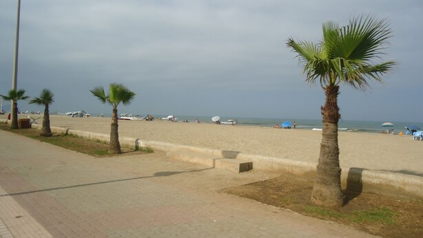 A beach with palm trees, beach umbrellas, and a clear sky. - Martil apartment facing the sea (Martil)