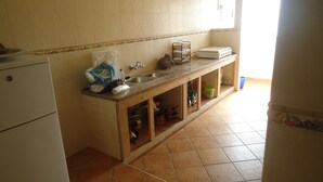 A kitchen with a refrigerator, sink, and cabinets. - Martil apartment facing the sea (Martil)