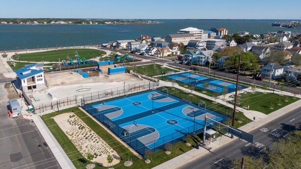 Eine Luftaufnahme eines Sportkomplexes mit mehreren Basketballplätzen, einem Spielplatz und einem Parkplatz.