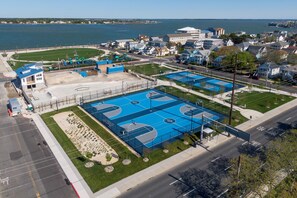 Vue aérienne d’un complexe sportif comprenant plusieurs terrains de basket-ball, une aire de jeux et un parking.