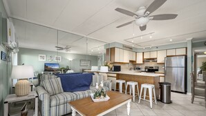 Une cuisine moderne dotée d’un îlot central, d’un coin repas avec un canapé à rayures et d’un ventilateur de plafond.