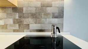A modern kitchen with a black induction cooktop and a stainless steel kettle. - THE CEMENT TILES (Catania)