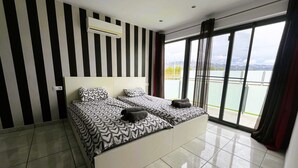 A modern hotel room with a large bed, striped walls, and a balcony with a view.
