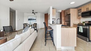 A modern kitchen with wooden cabinets, a central island, and a dining area with a sofa and chairs. - Victoria Marine’s View | Modern 3BR in Fajardo (Fajardo)