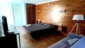 Une chambre moderne avec un mur en bois, un lit avec une literie à rayures, un canapé bleu et un bureau avec une lampe.