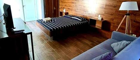 Une chambre moderne avec un mur en bois, un lit avec une literie à rayures, un canapé bleu et un bureau avec une lampe.