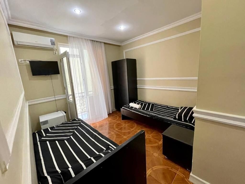A room with two beds, a flat-screen TV, an air conditioner, and a large speaker.