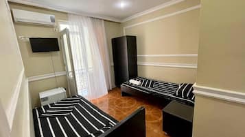 Una habitación con dos camas, un televisor de pantalla plana, aire acondicionado y un altavoz grande.