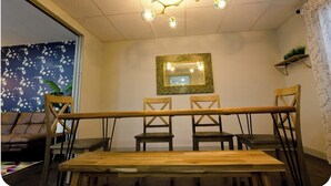 Un coin repas avec une table et des chaises en bois, un lustre et un miroir au mur.